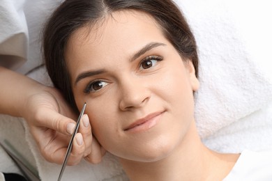 Photo of Woman undergoing lash extensions procedure in beauty salon, top view