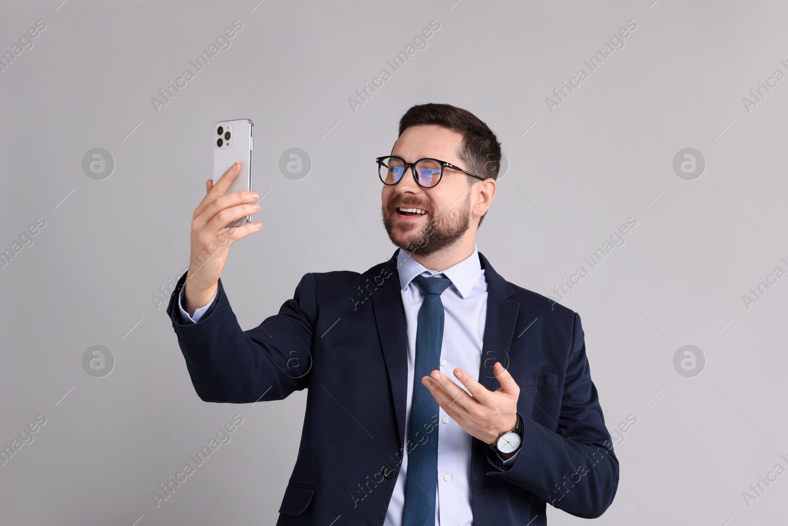 Photo of Banker having video chat via smartphone on grey background