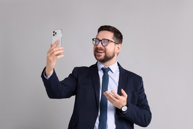 Banker having video chat via smartphone on grey background