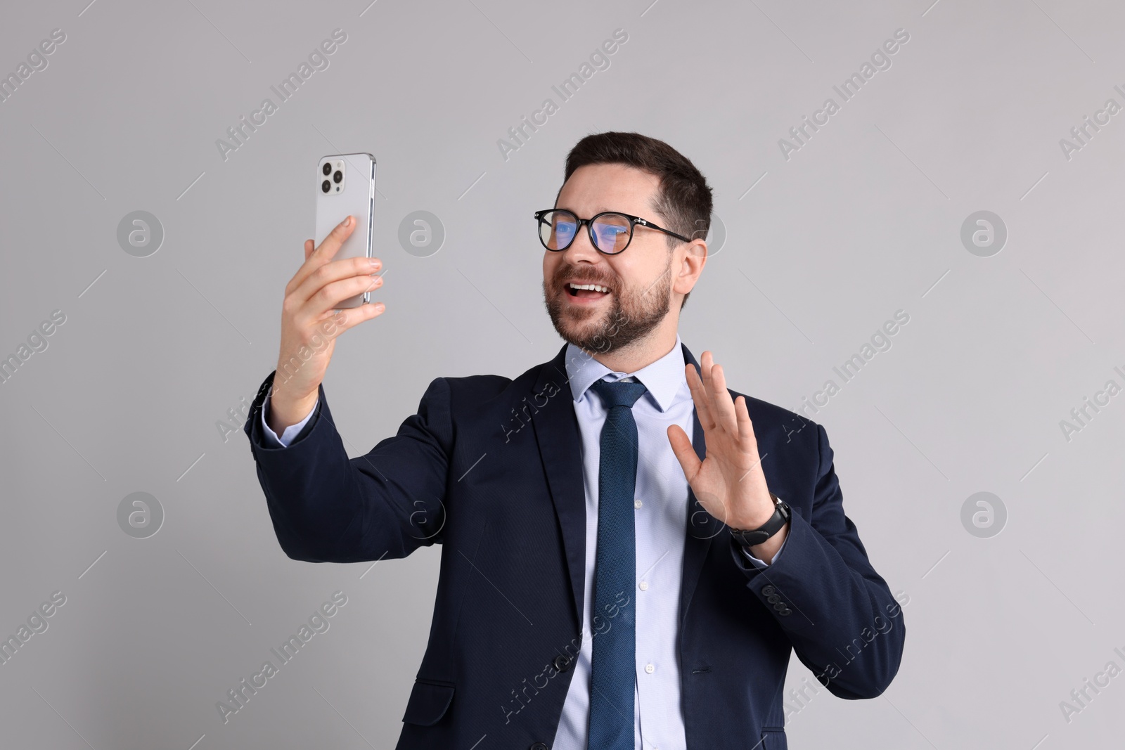 Photo of Banker having video chat via smartphone on grey background