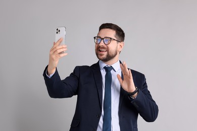 Banker having video chat via smartphone on grey background