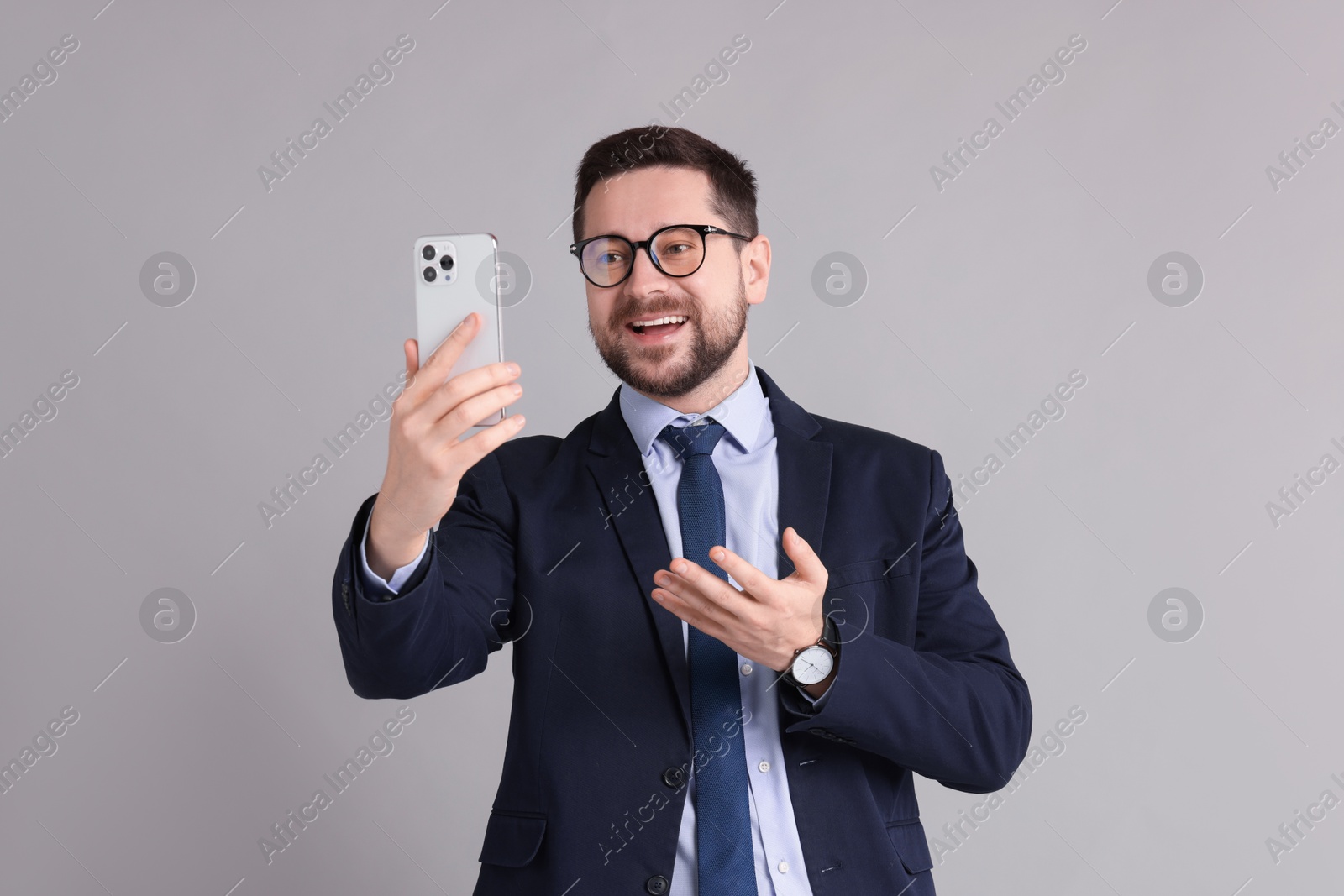 Photo of Banker having video chat via smartphone on grey background