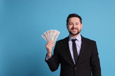 Banker with dollar banknotes on light blue background, space for text