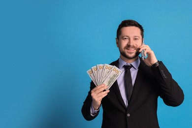 Photo of Banker with dollar banknotes talking on smartphone against light blue background, space for text