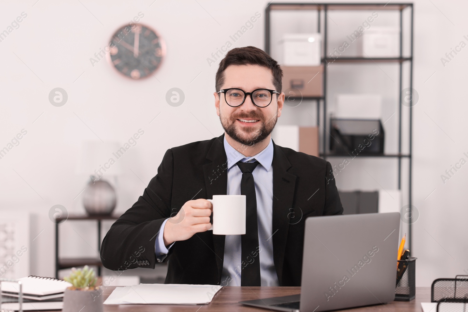 Photo of Banker with cup of drink at wooden table in office