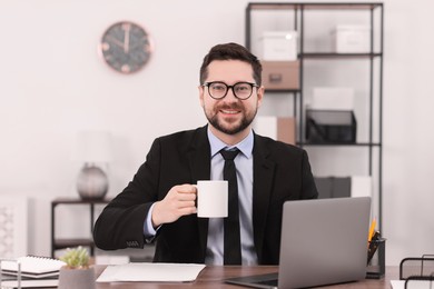 Photo of Banker with cup of drink at wooden table in office