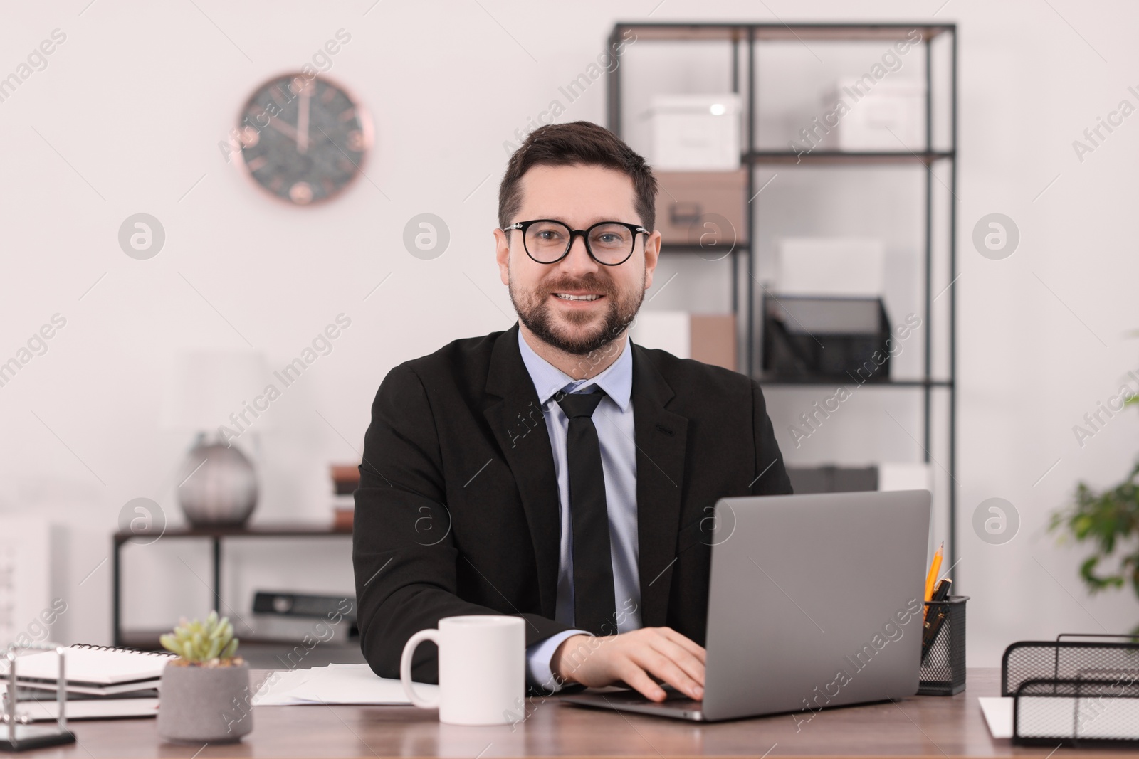 Photo of Banker working with laptop at wooden table in office