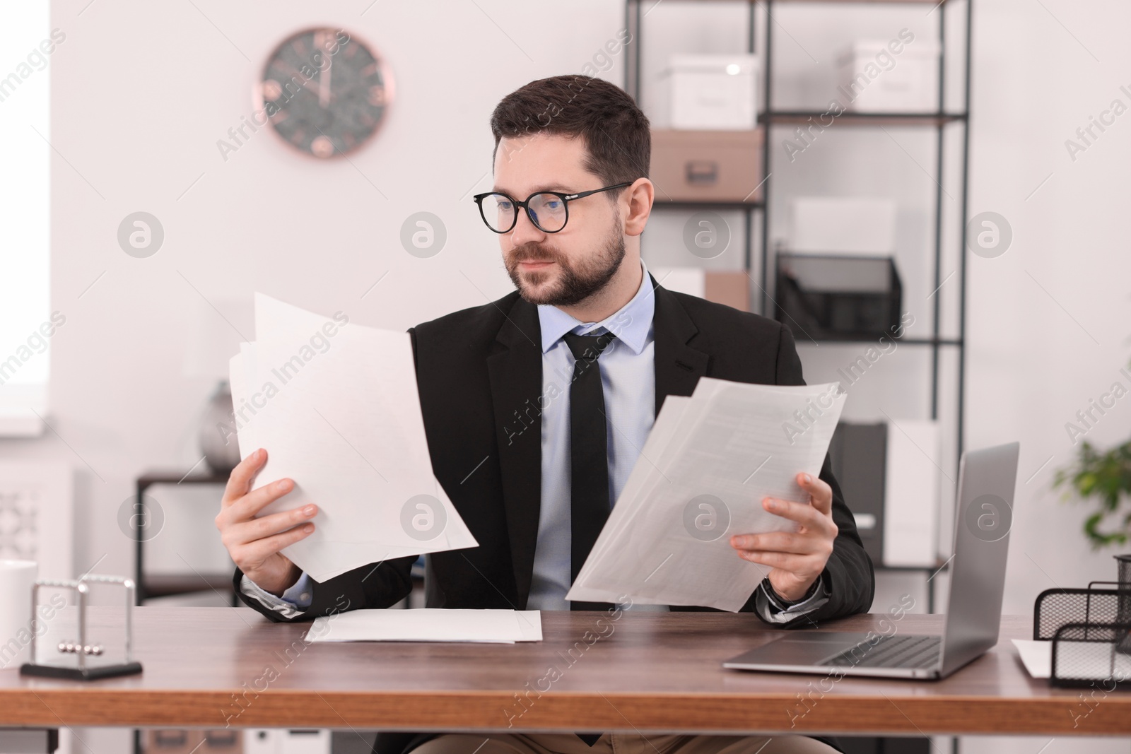 Photo of Banker working with documents at wooden table in office