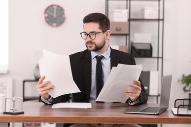 Photo of Banker working with documents at wooden table in office