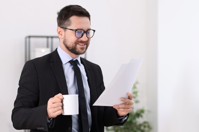 Photo of Banker with cup of drink and documents in office