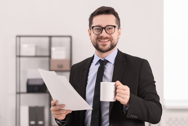 Banker with cup of drink and documents in office