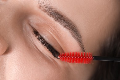 Photo of Eyelash extension procedure. Woman combing lashes with brush, closeup