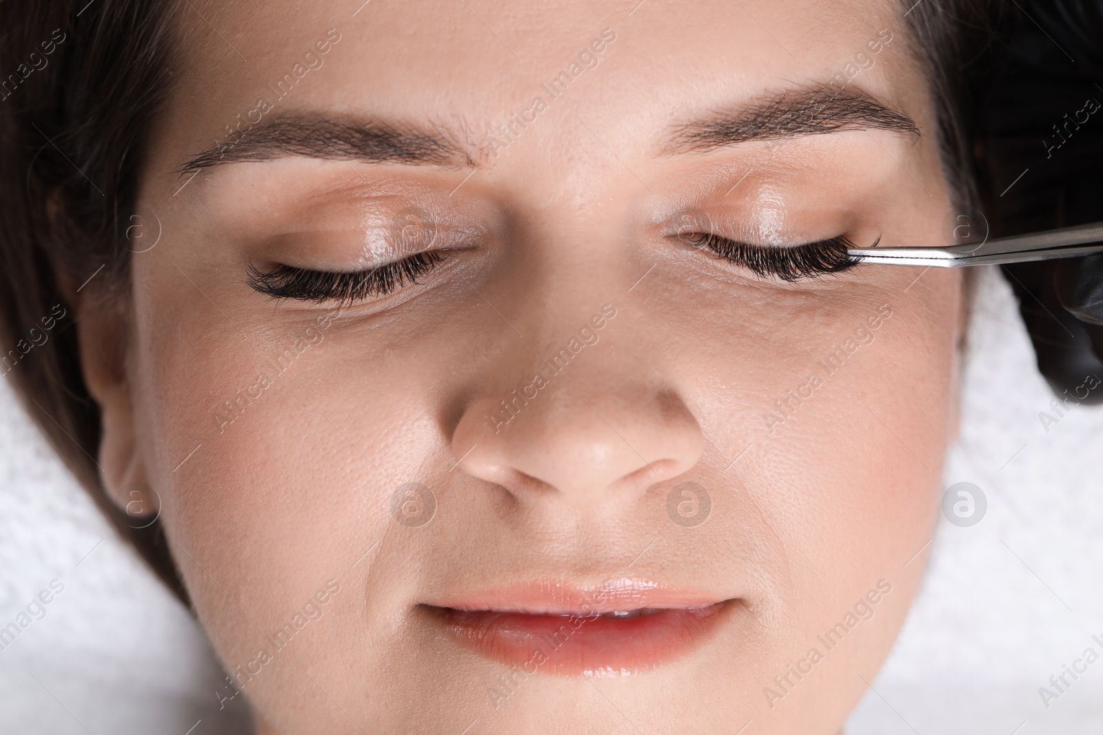 Photo of Woman undergoing lash extensions procedure in beauty salon, top view