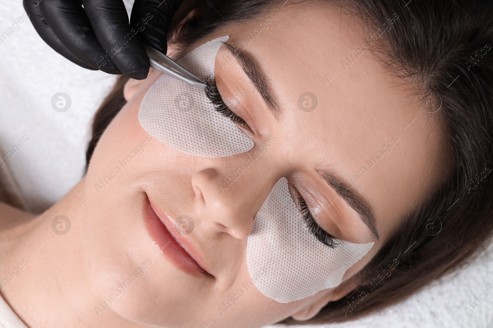 Photo of Woman undergoing lash extensions procedure in beauty salon, top view