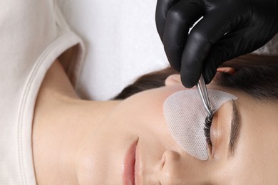 Photo of Woman undergoing lash extensions procedure in beauty salon, top view