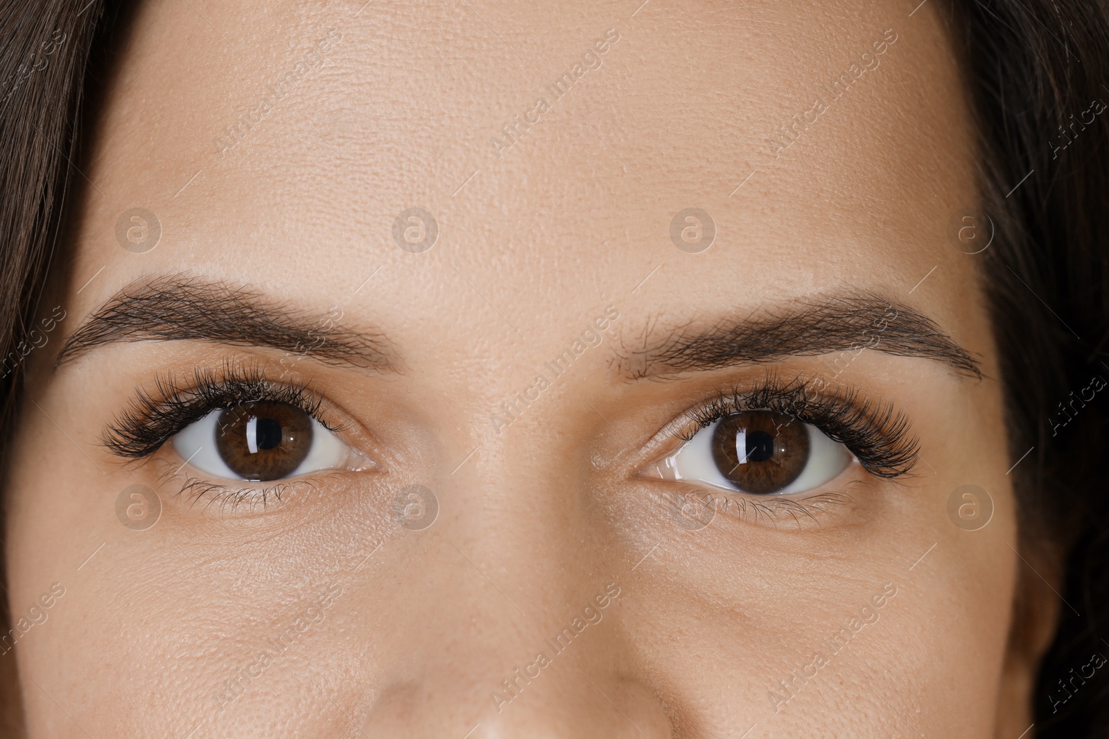 Photo of Woman with beautiful long eyelashes, closeup. Eyelash extension procedure