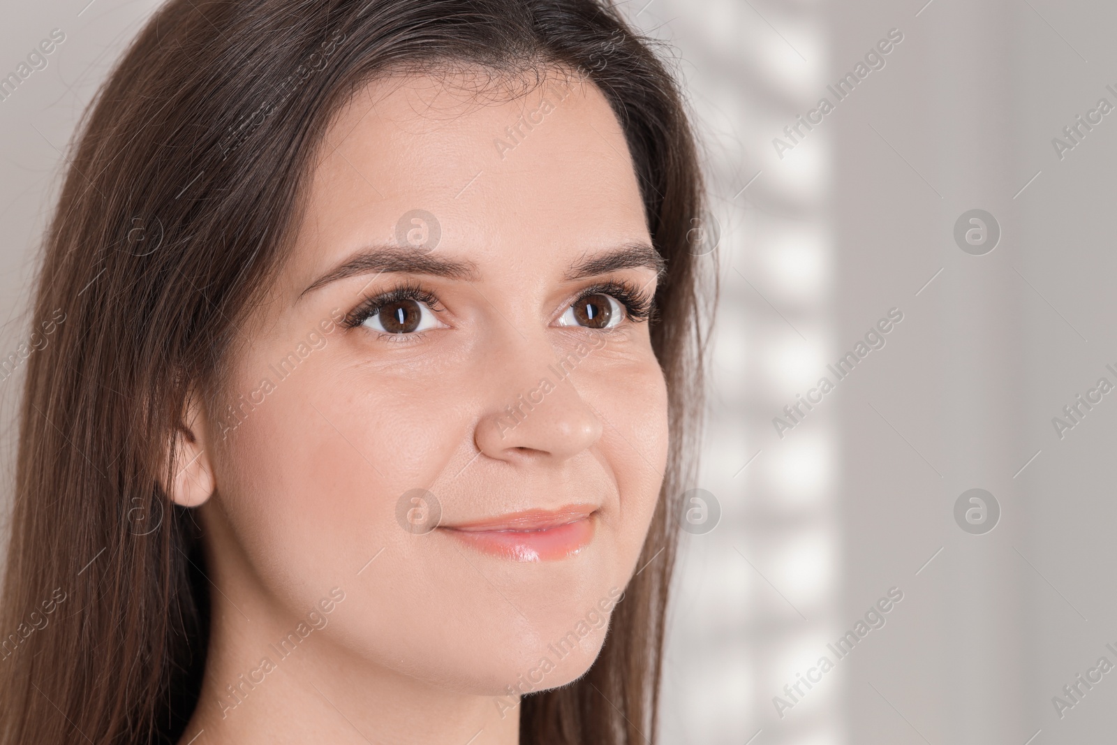 Photo of Eyelash extension procedure. Woman with beautiful long eyelashes on light background, closeup. Space for text