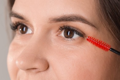 Photo of Eyelash extension procedure. Woman combing lashes with brush, closeup