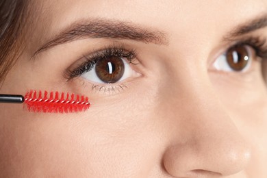 Eyelash extension procedure. Woman combing lashes with brush, closeup