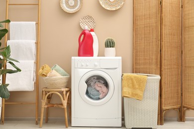 Photo of Wicker laundry basket, washing machine and detergents in bathroom