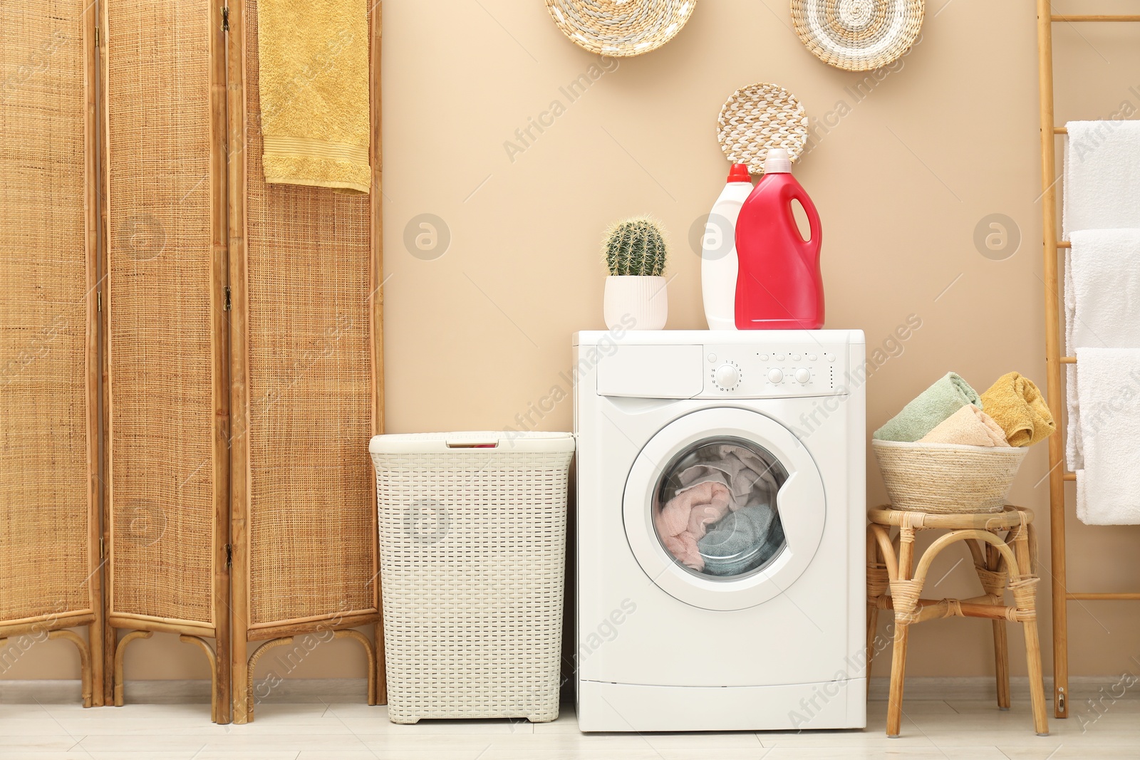 Photo of Wicker laundry basket, washing machine and detergents in bathroom