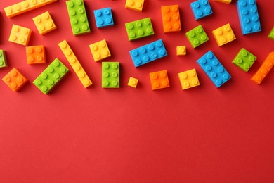 Photo of Construction toy. Colorful building bricks on red background, flat lay