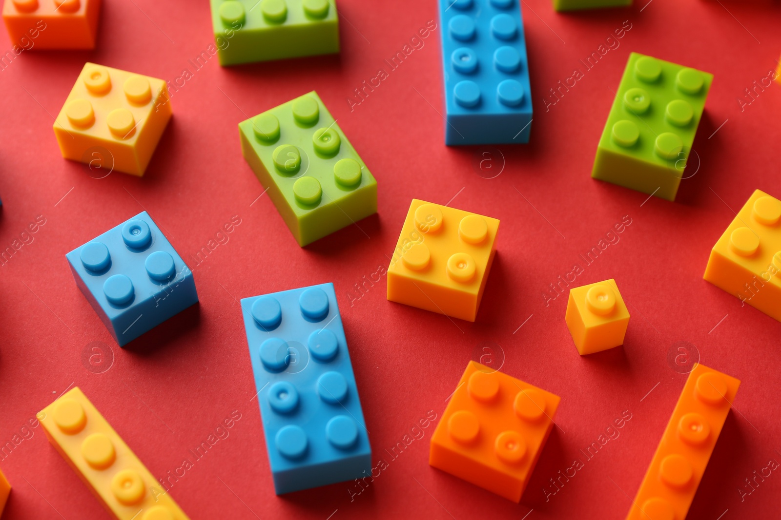 Photo of Construction toy. Colorful building bricks on red background, closeup