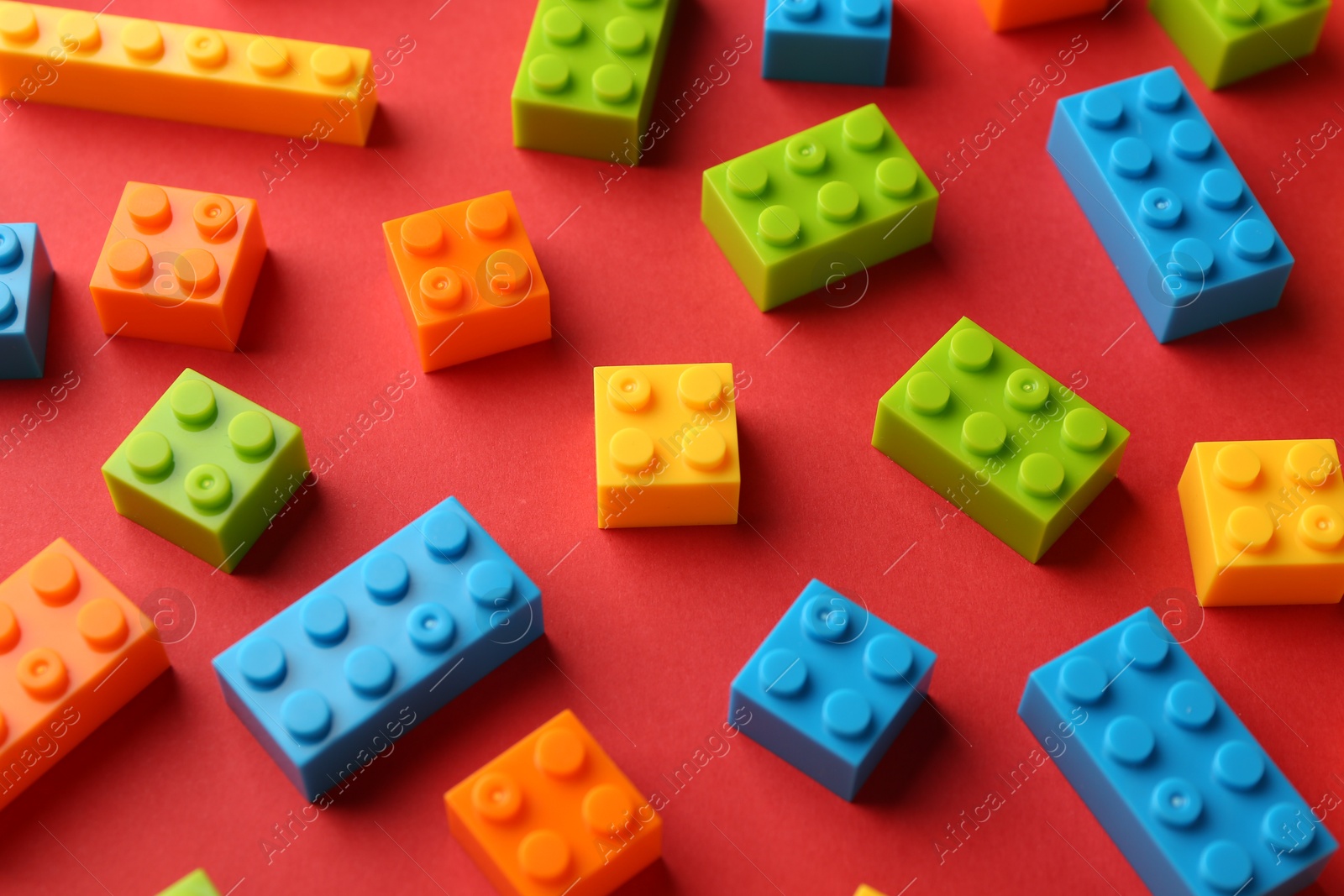 Photo of Construction toy. Colorful building bricks on red background, closeup