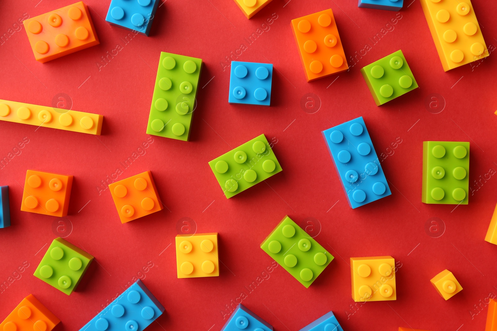 Photo of Construction toy. Colorful building bricks on red background, flat lay