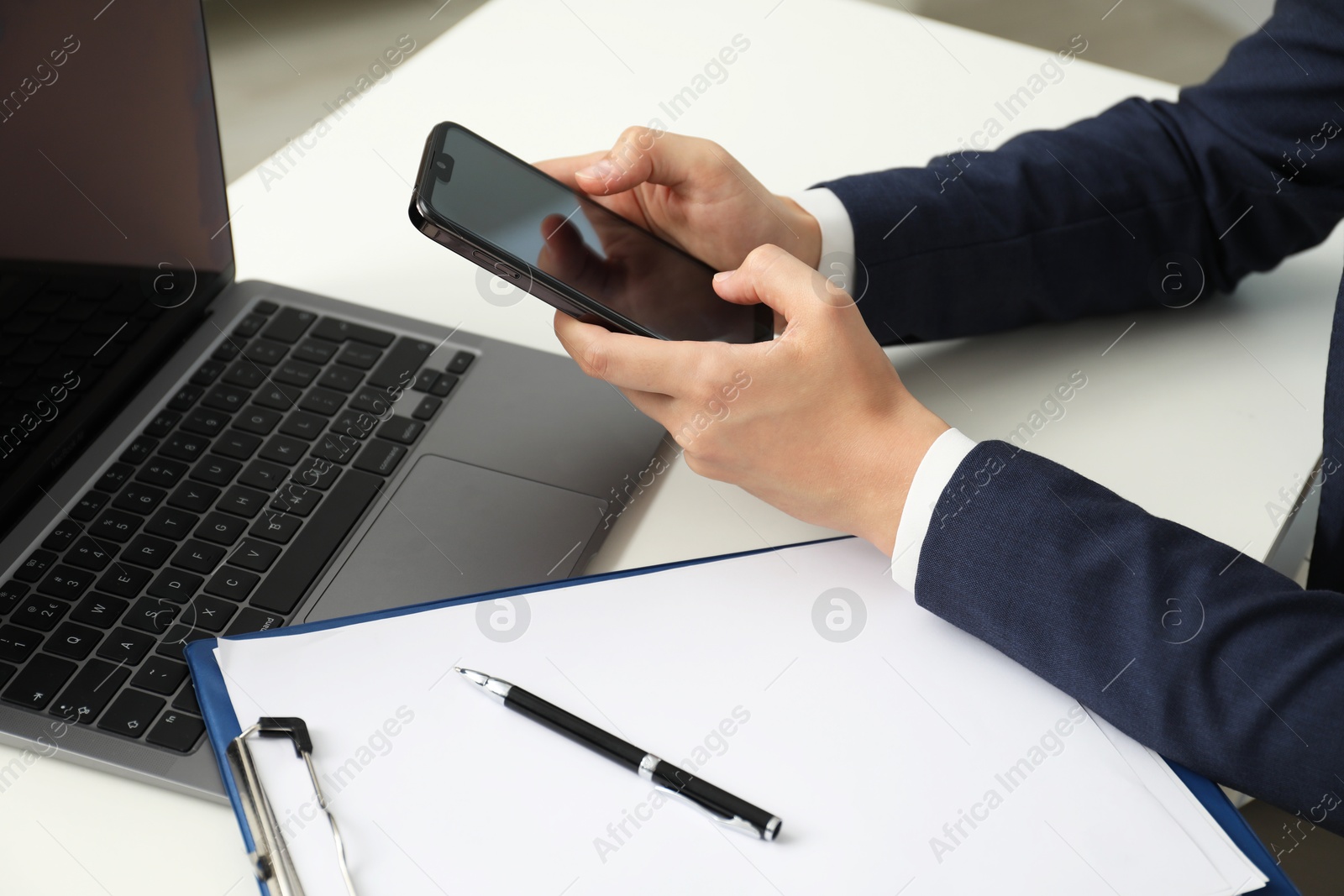 Photo of Businesswoman using smartphone at white table indoors, closeup. Modern technology