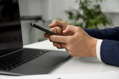 Photo of Businesswoman using smartphone at white table indoors, closeup. Modern technology