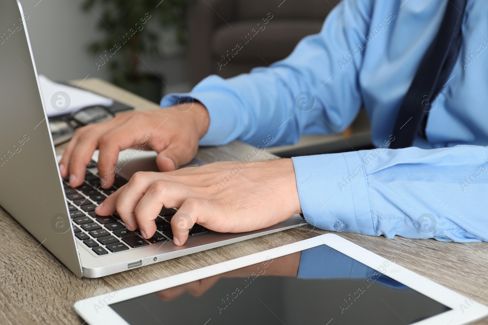 Photo of Businessman with laptop and tablet at wooden table, closeup. Modern technology