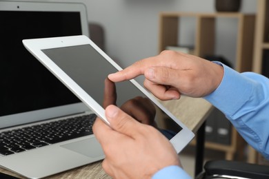 Photo of Businessman using tablet at table, closeup. Modern technology