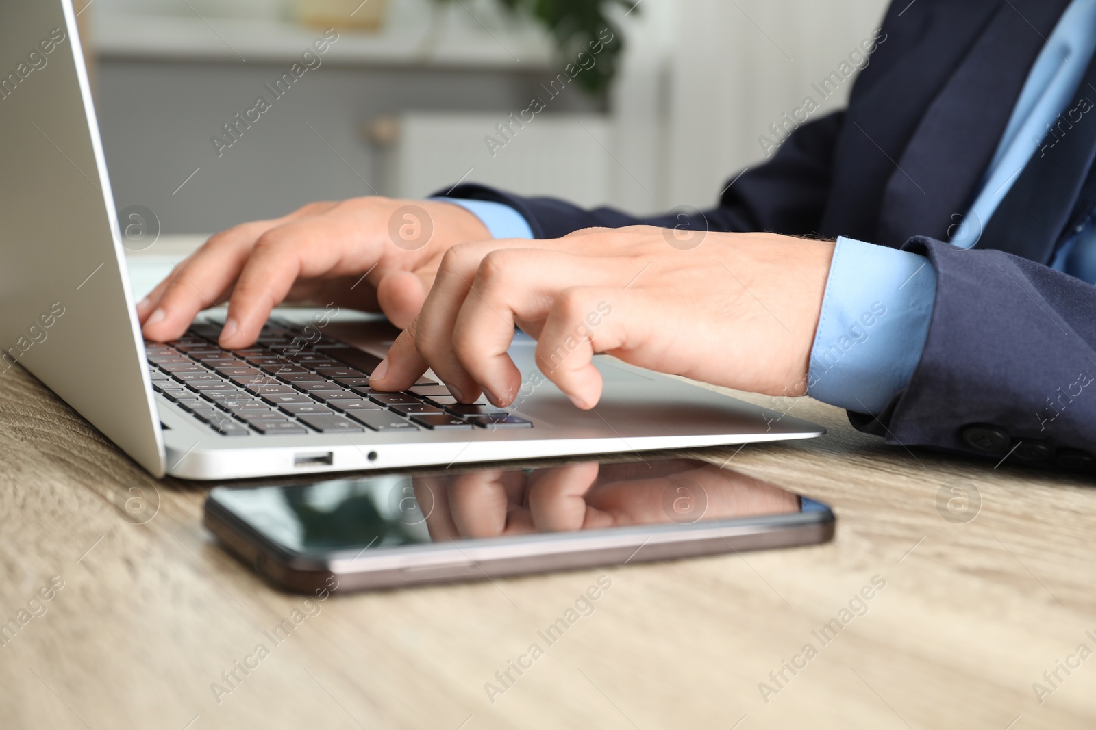 Photo of Businessman using laptop at wooden table, closeup. Modern technology