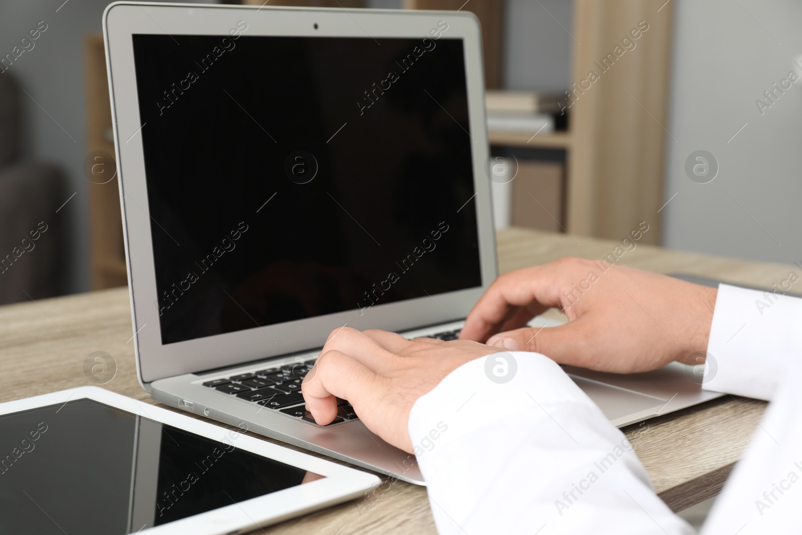 Photo of Businessman using laptop at wooden table, closeup. Modern technology