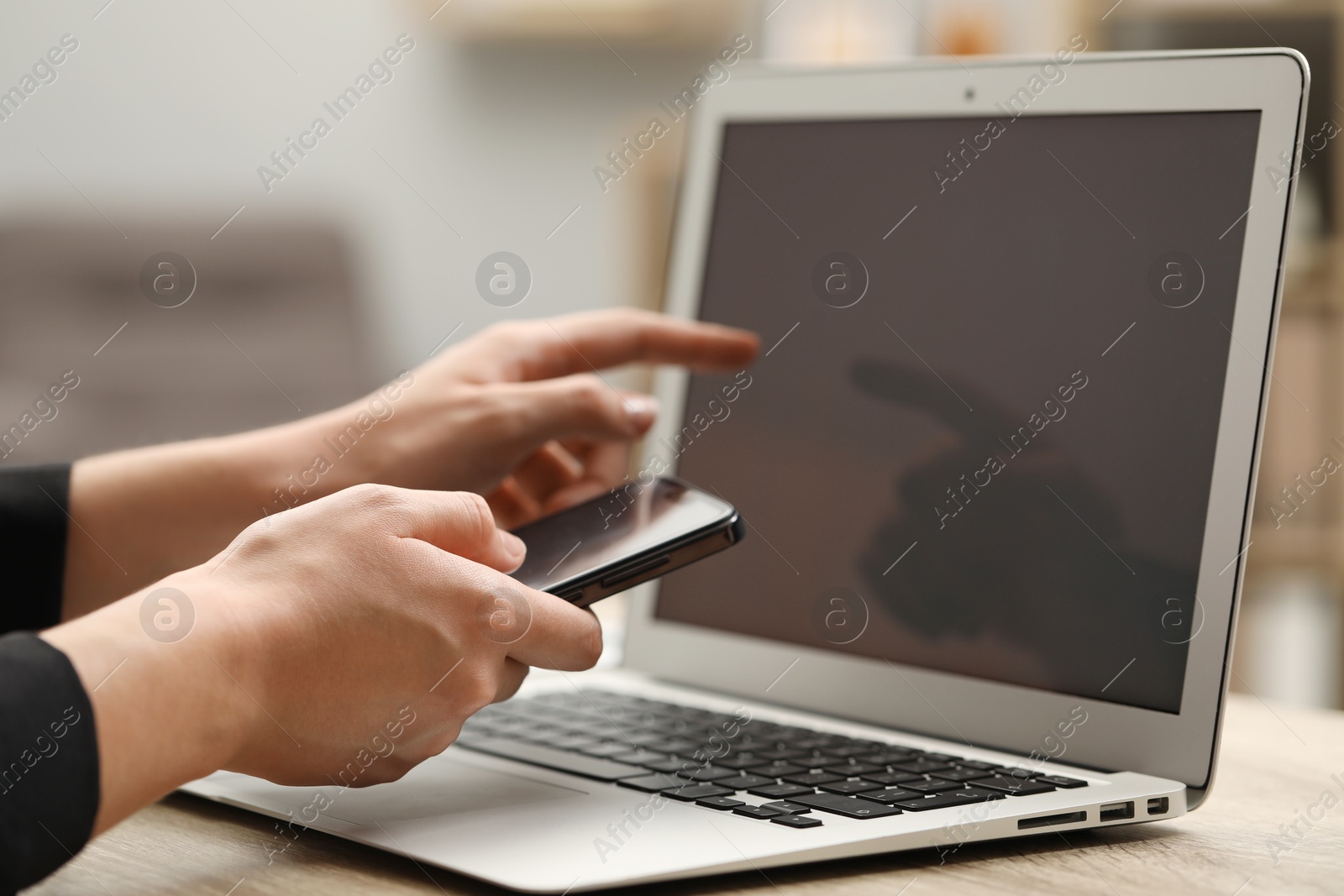 Photo of Businessman with smartphone near laptop at table, closeup. Modern technology