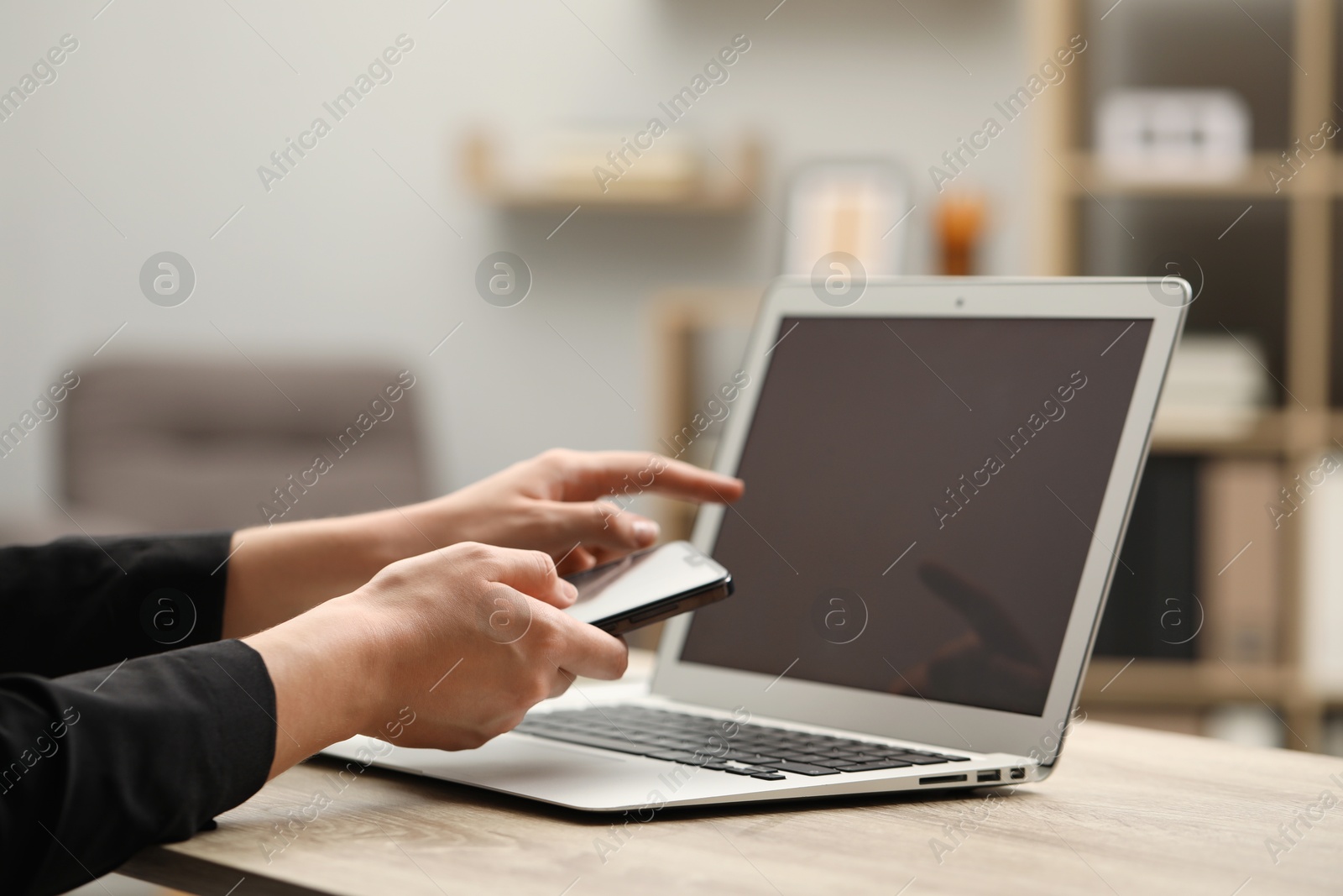 Photo of Businessman with smartphone near laptop at table, closeup. Modern technology