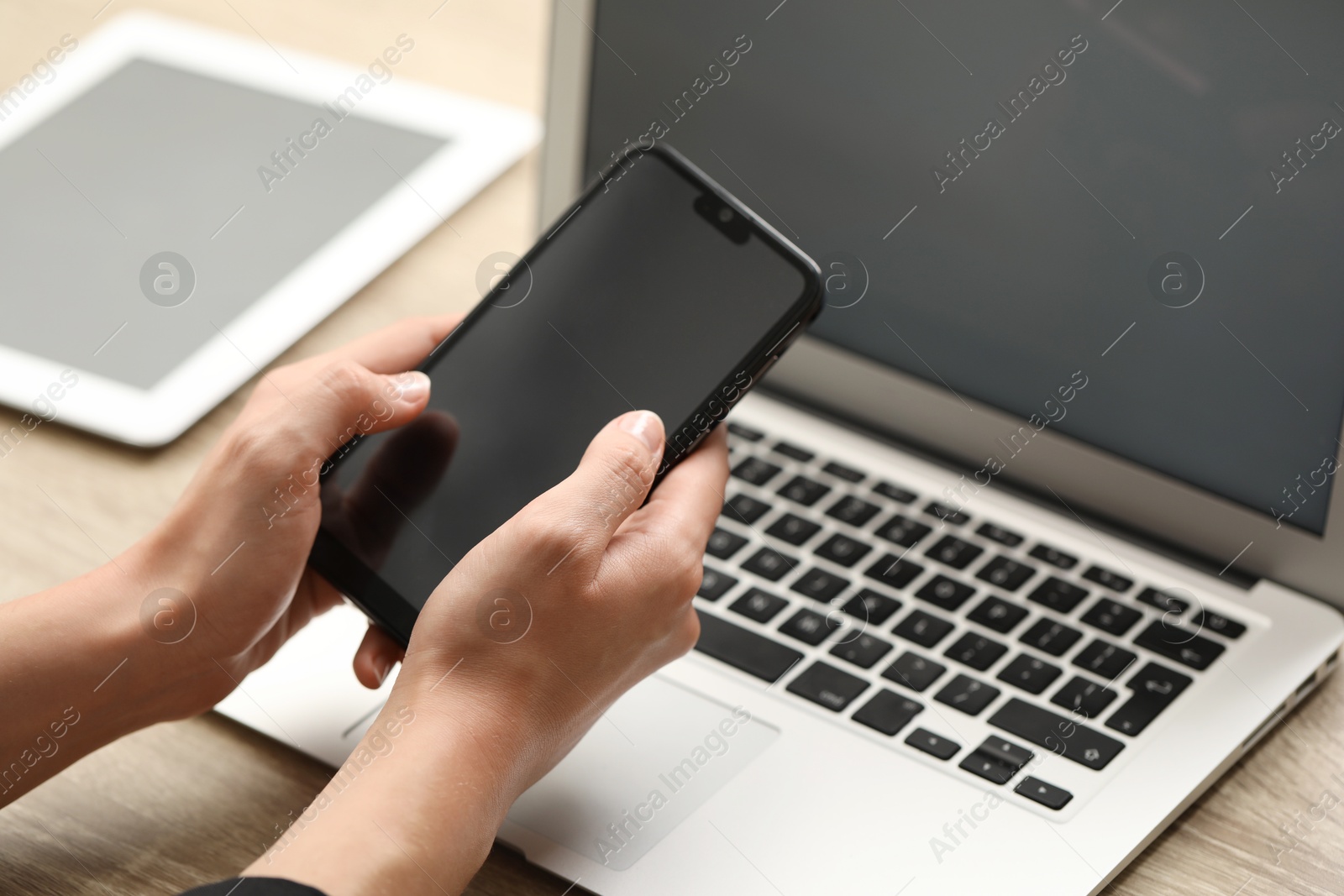 Photo of Businessman with smartphone near laptop at table, closeup. Modern technology