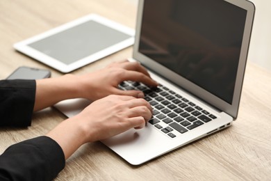 Photo of Businessman using laptop at wooden table, closeup. Modern technology