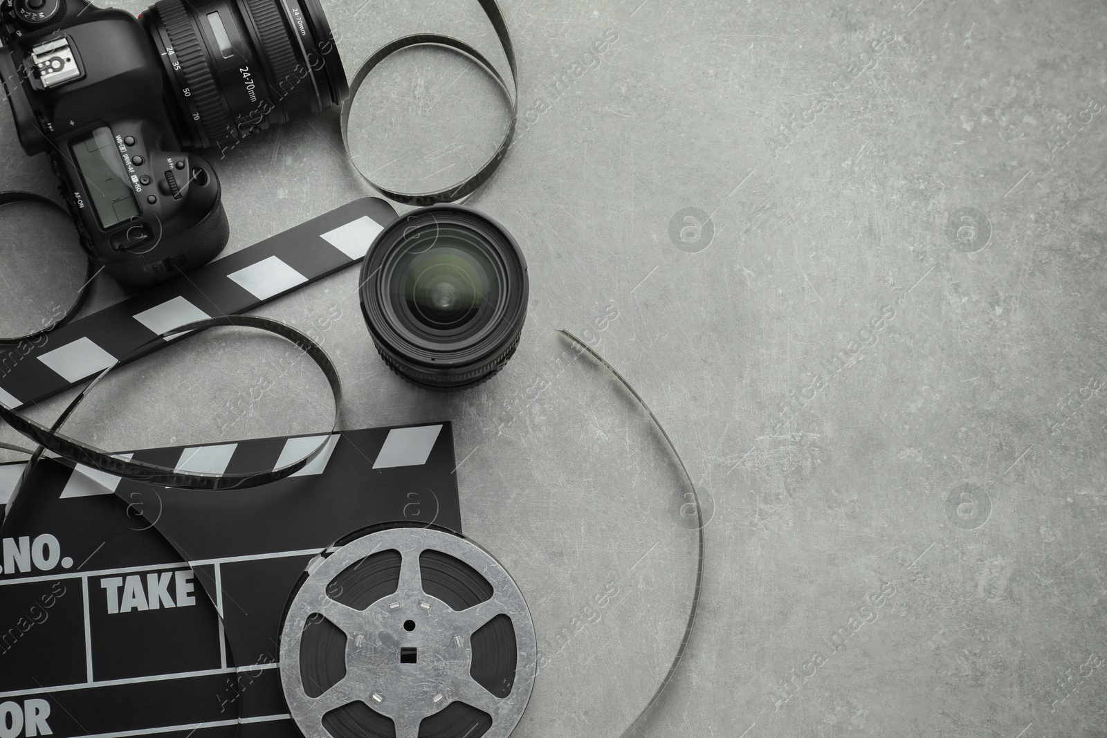 Photo of Movie clapper, film reel and camera on grey textured table, flat lay. Space for text