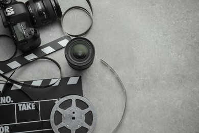 Photo of Movie clapper, film reel and camera on grey textured table, flat lay. Space for text