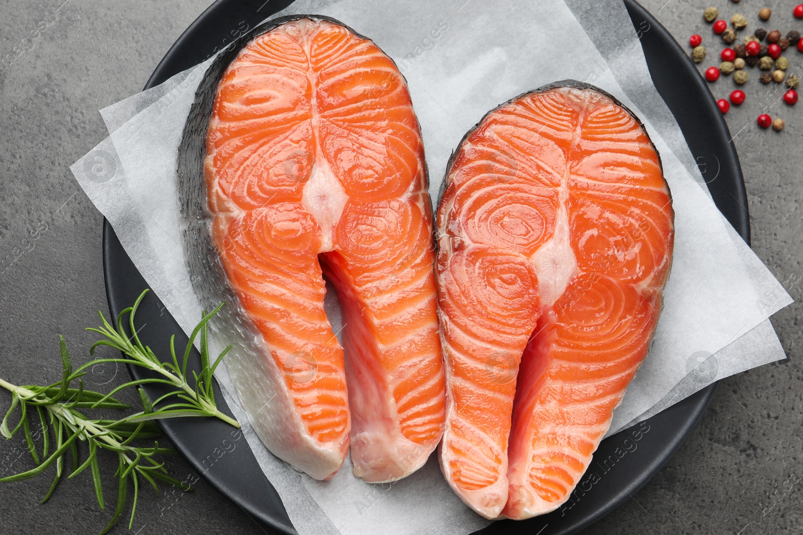 Photo of Fresh raw salmon steaks and spices on grey textured table, top view