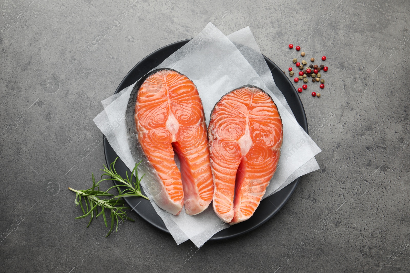 Photo of Fresh raw salmon steaks and spices on grey textured table, top view