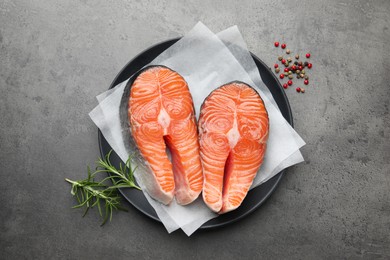 Photo of Fresh raw salmon steaks and spices on grey textured table, top view