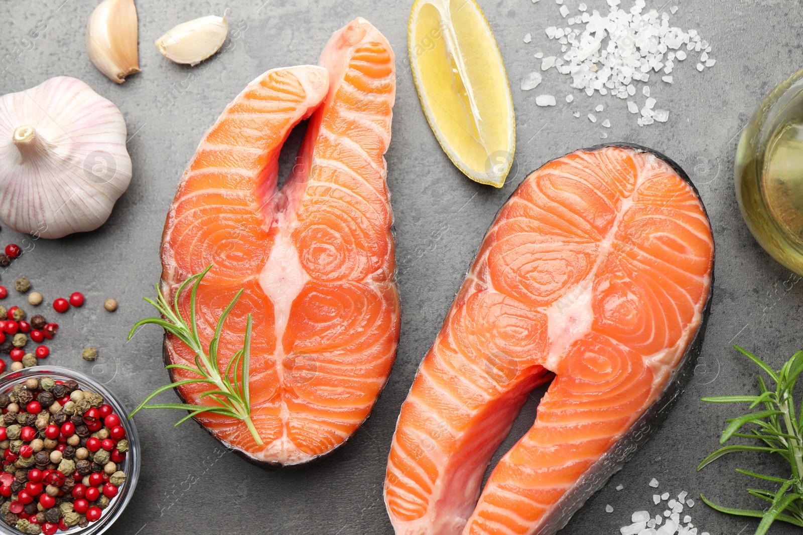 Photo of Fresh raw salmon steaks and spices on grey textured table, flat lay