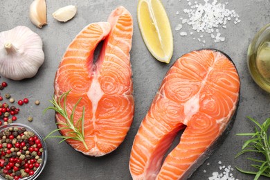 Photo of Fresh raw salmon steaks and spices on grey textured table, flat lay