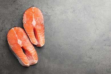 Photo of Fresh raw salmon steaks on grey textured table, top view. Space for text