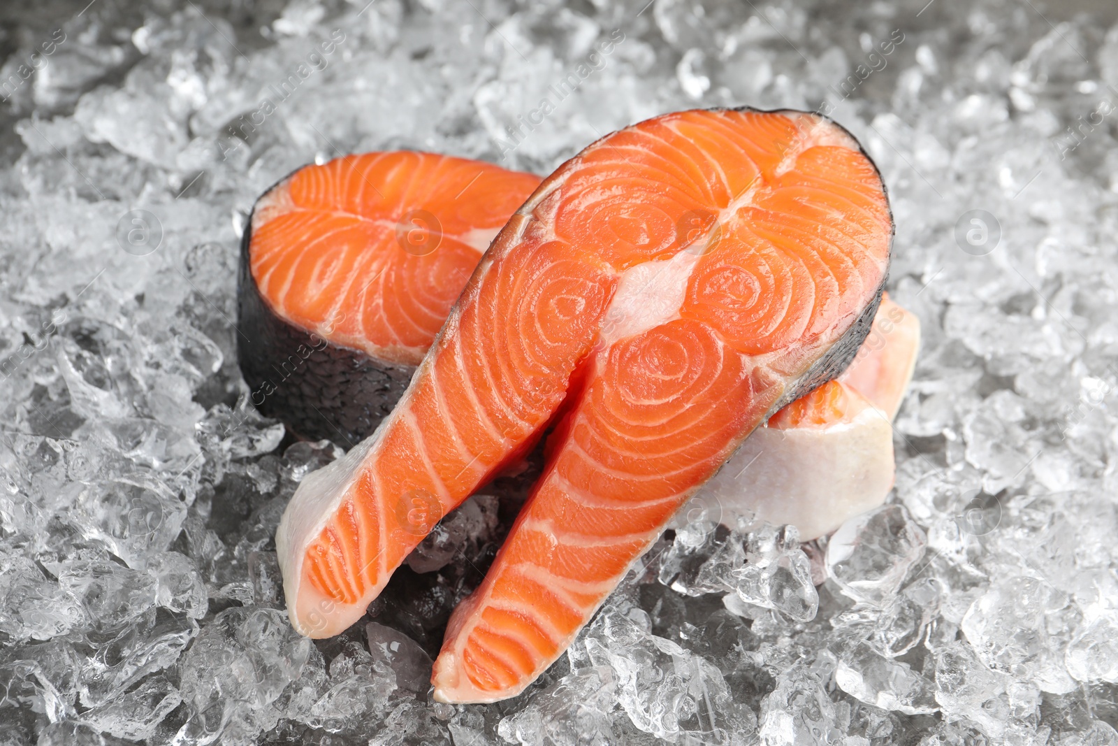 Photo of Fresh raw salmon steaks on ice pieces, closeup