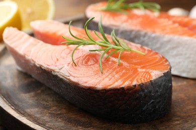 Fresh raw salmon steaks and rosemary on table, closeup