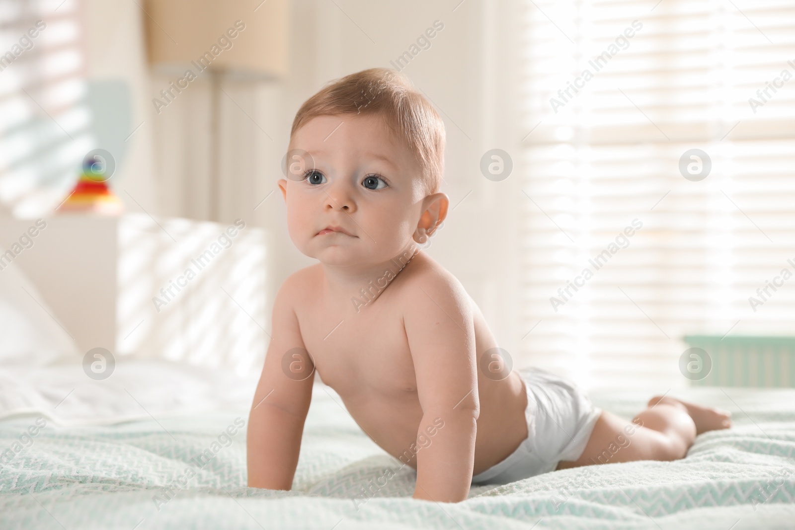 Photo of Cute little baby in diaper on bed at home